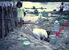 Shallow hand dug community well next to a contaminated river.